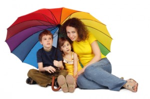 mother, daughter and son with big multicolored umbrella sitting